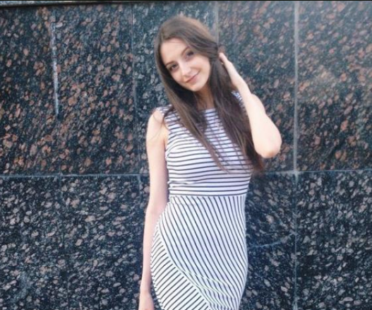 Woman in dress standing against a textured wall