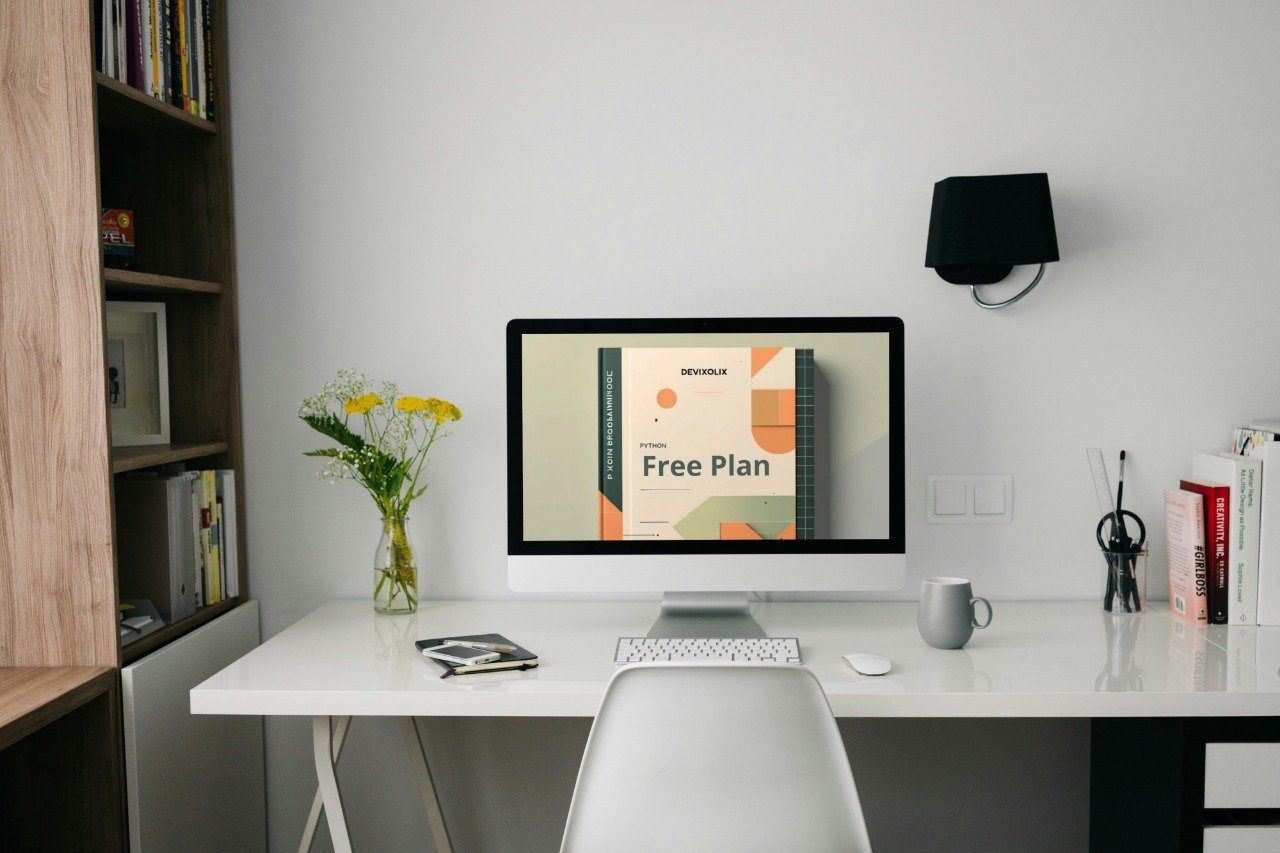 Modern office desk with computer, mug, and books in a home office setting.
